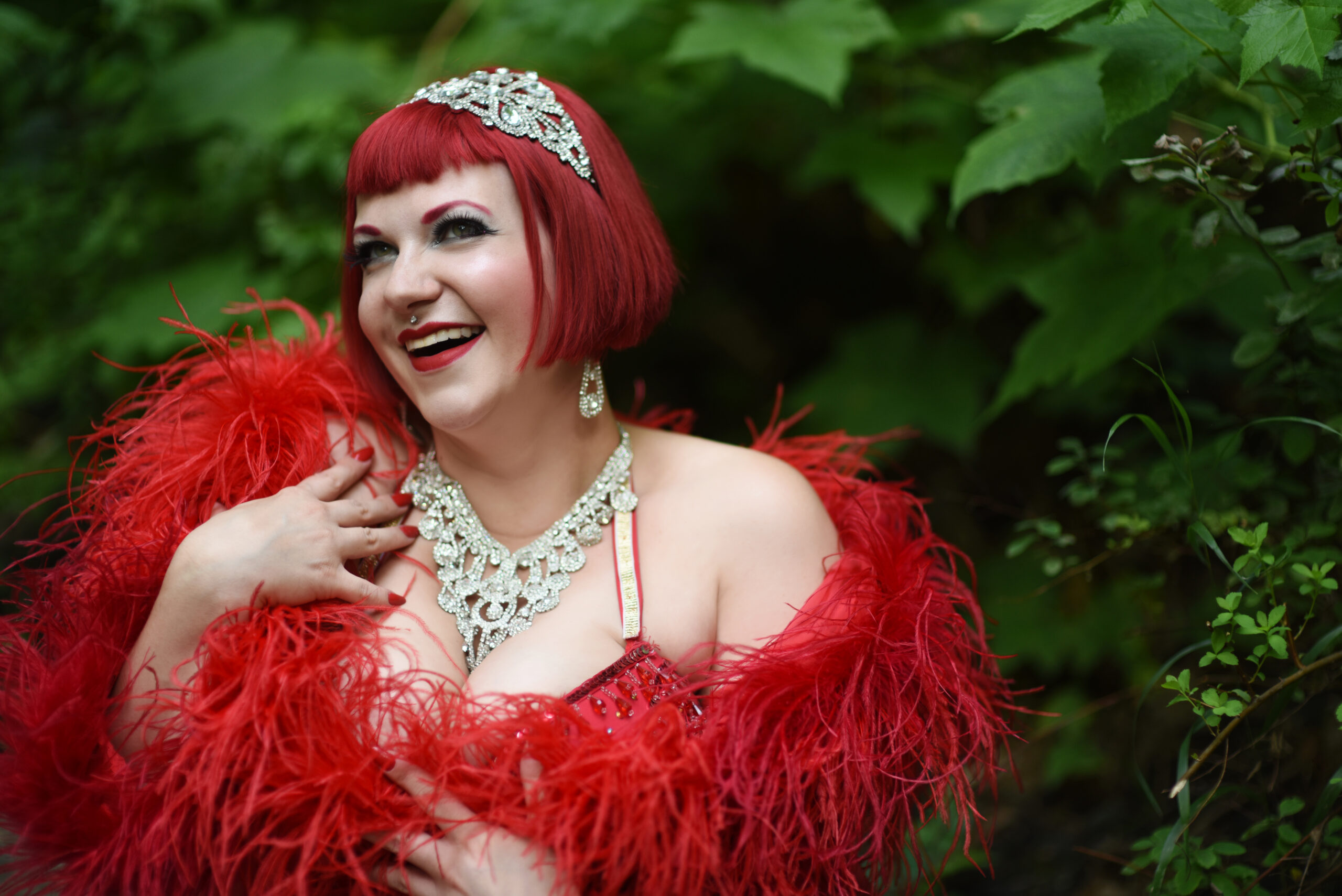 Smiling performer in red feather outfit outdoors