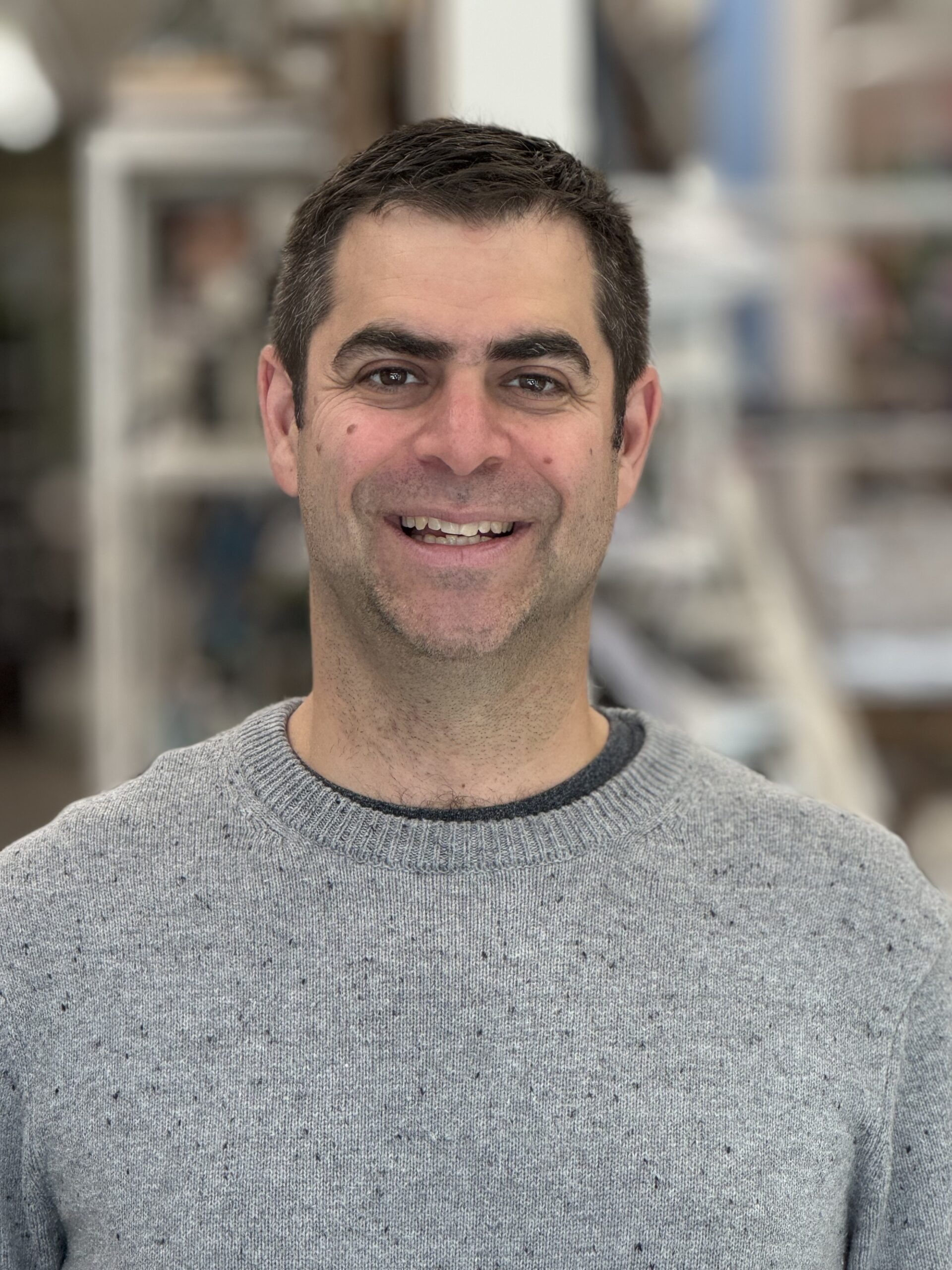 Smiling man wearing gray sweater indoors