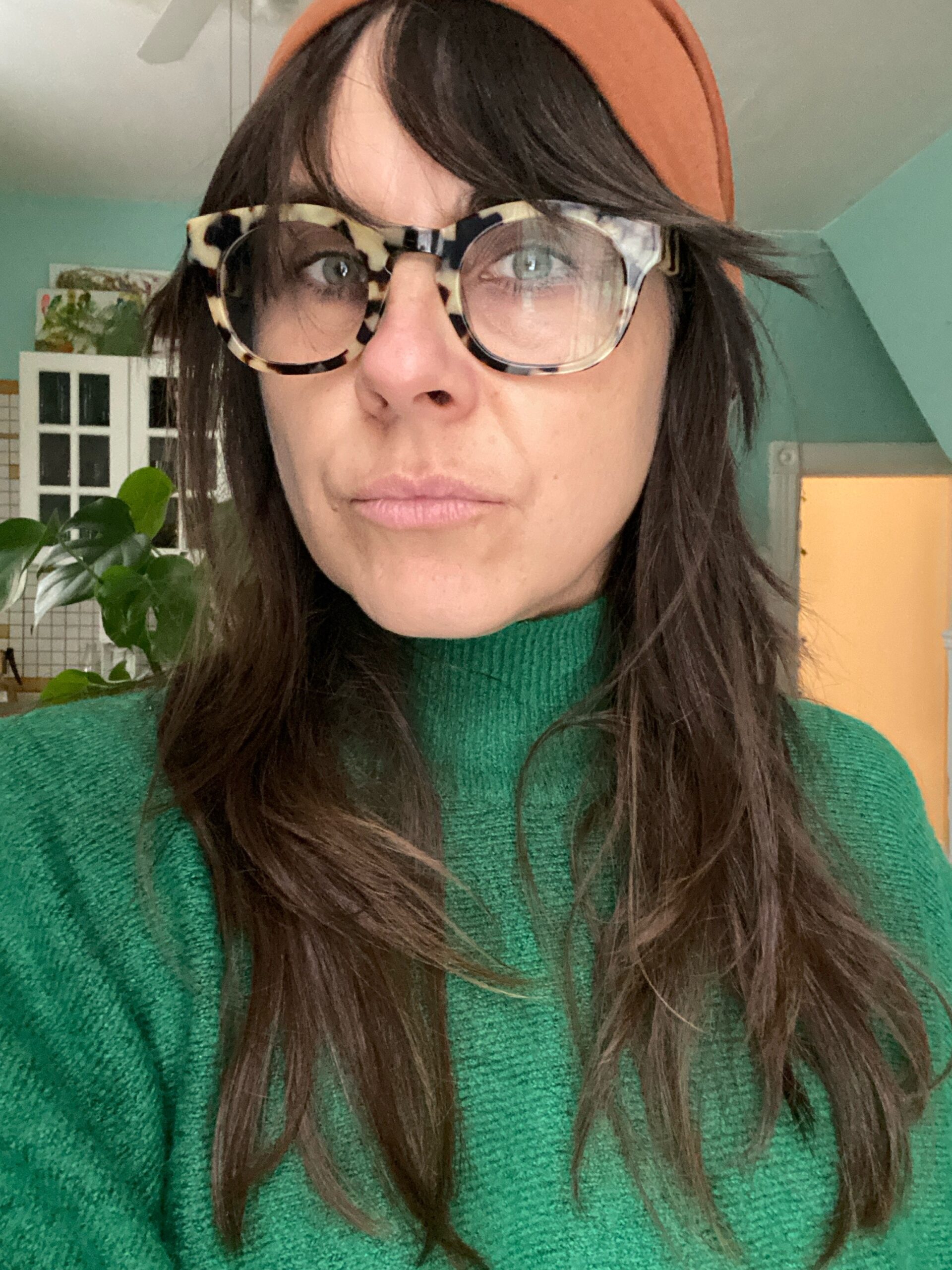 Person wearing glasses and green sweater indoors